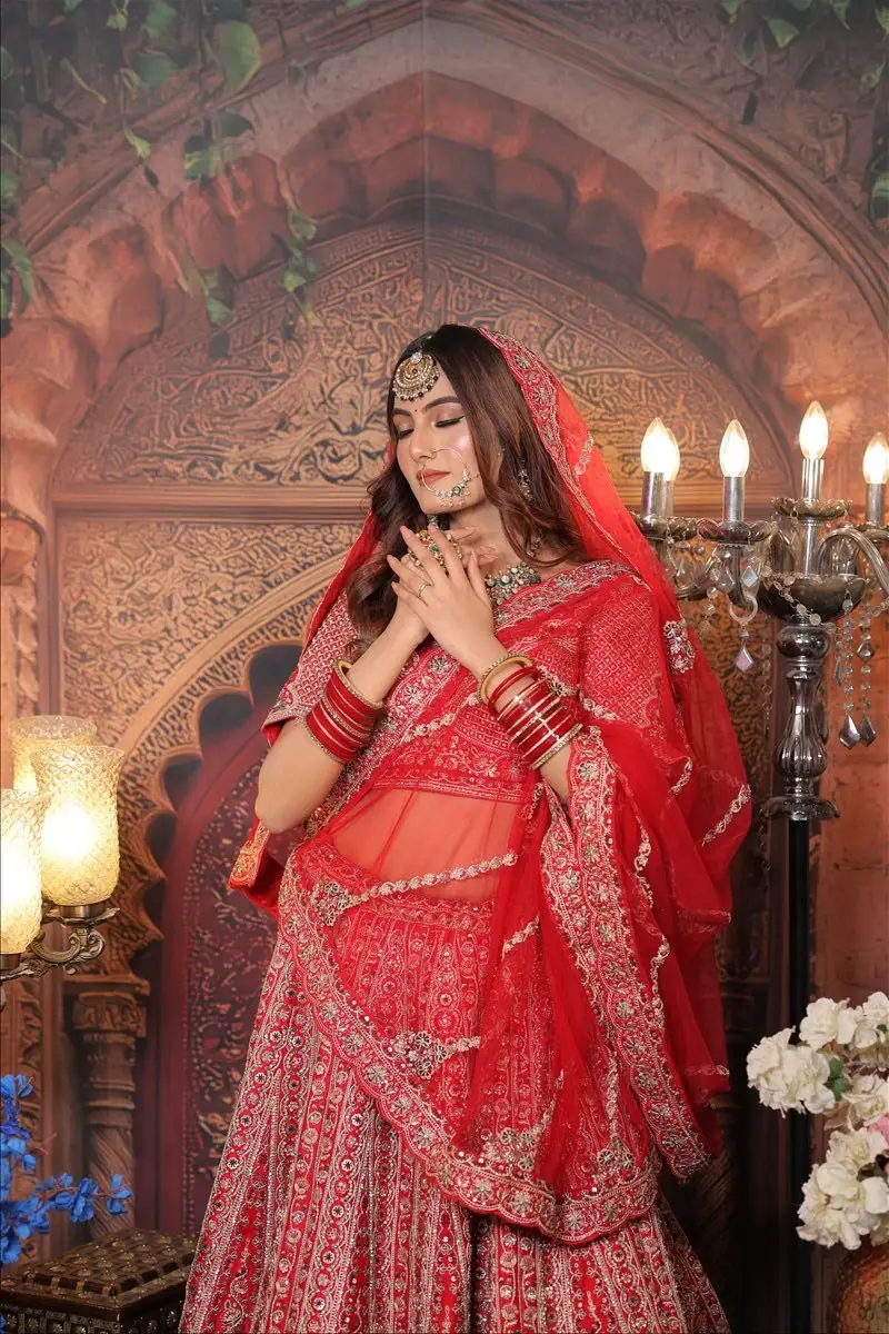 Bride in a red lehenga wearing bridal makeup by Priyanshi